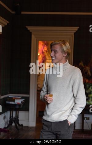 Stylish handsome young caucasian man enjoying whiskey in an elegant room. Stock Photo