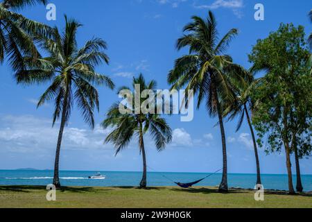 A man relaxing in a hammock with a view of the Coral Sea and Snapper Island from Rex Smeal Park in Port Douglas, Queensland, Australia Stock Photo