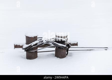 Mooring bollard with steel rope covered with snow, close up photo Stock Photo