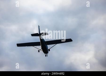 Light aircraft silhouette is in cloudy sky on a daytime, close up rear view Stock Photo