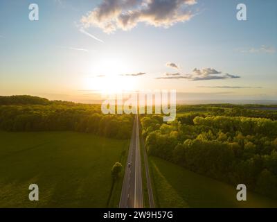 An aerial view of a straight road going through a forest at sunset in Giessen, Hessen, Germany Stock Photo
