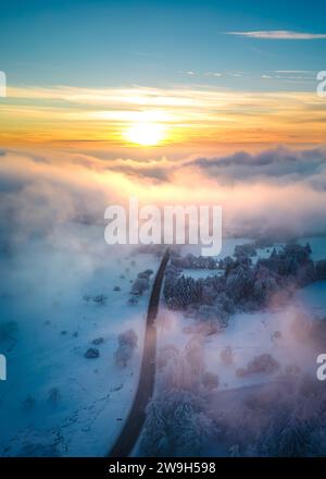 An aerial view of a mountain road going through a snow-covered landscape at sunset in Vogelsberg, Germany Stock Photo
