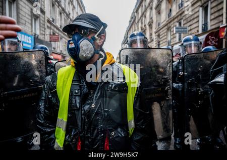 Paris, France. 18th Nov, 2023. A 'yellow vest' anti-government protester is seen with a gas mask with police officers in his background during the demonstration. 'Yellow vests” (gilets jaunes) anti-government protesters gathered in Paris on their 5th anniversary of the movement to show the government that they are still alive and over the years they have increased in number. (Photo by Maria Giulia Molinaro Vitale/SOPA Images/Sipa USA) Credit: Sipa USA/Alamy Live News Stock Photo