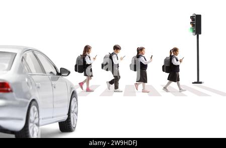 Schoolchildren with mobile phones crossing a street in front of a car isolated on white background Stock Photo