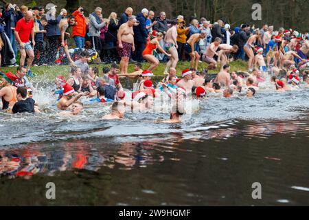 The annual Christmas morning dip into Blackroot Pool in Sutton Coldfield Park. On the stroke of 10am, people dressed in festive costumes, dive, jump, lower themselves into the water. Stock Photo