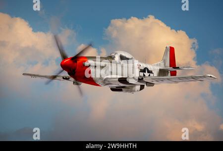 P-51 Mustang World War II era fighter flies among clouds and blue sky. (Detailed model, not a real airplane) Stock Photo