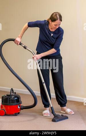 Woman using a vacuum cleaner to clean carpet Stock Photo