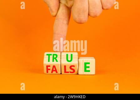 False or true symbol. Turned wooden cubes and changed the word false to true or vice versa. Beautiful orange table, orange background, copy space. Bus Stock Photo