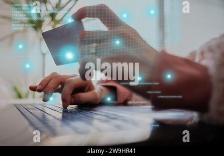 Conceptual image of online banking and shopping - closeup view of female hands holding a credit card while typing on laptop computer with virtual bina Stock Photo