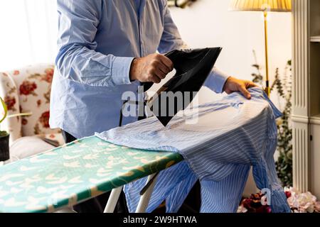 Detail of a man's hand with an iron in his hand while ironing his shirt Stock Photo