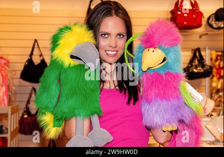 Inside a boutique store, a glamorous woman has fun modelling while playing with glove puppets in  Dundee, Scotland Stock Photo