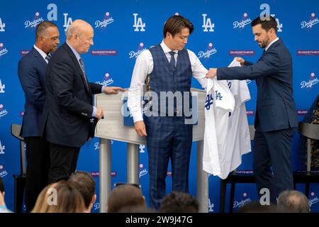 Los Angeles, California, USA. 27th Dec, 2023. BRANDON GOMES, Executive Vice President and General Manager of the Los Angeles Dodgers helps newly signed Dodger pitcher YOSHINOBU YAMAMOTO put on his jersey at his introductory press conference at Dodger Stadium on December 27, 2023. (Credit Image: © Mark Edward Harris/ZUMA Press Wire) EDITORIAL USAGE ONLY! Not for Commercial USAGE! Stock Photo