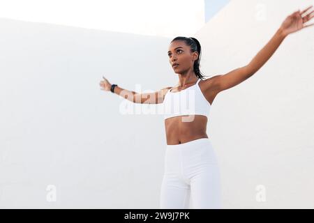 Young slim female jumping outdoors. Woman athlete warming up before training. Stock Photo