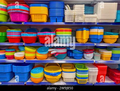 Multicolored plastic bowls, baskets and colanders and box on shelves for sale Stock Photo