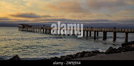 Swakopmund Pier jutting out into Atlantic Ocean against a stormy orangey blue sky Stock Photo