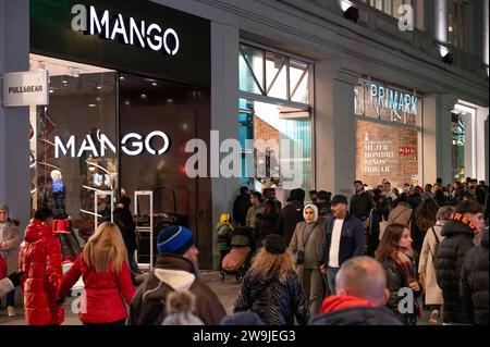 Shoppers and pedestrians walk past the Spanish multinational clothing design retail company Mango and Irish fashion retailer brand Primark stores in Spain. Stock Photo