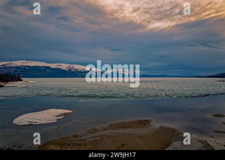 Drone image, view of the icy Atlin Lake, snowy mountain scenery behind, beautiful clouds, near Atlin, British Columbia, Canada Stock Photo