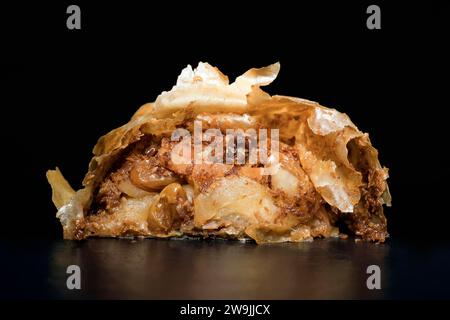 Austrian apple strudel with rum sultanas, cinnamon and very thin crispy strudel dough, food photography with black background Stock Photo