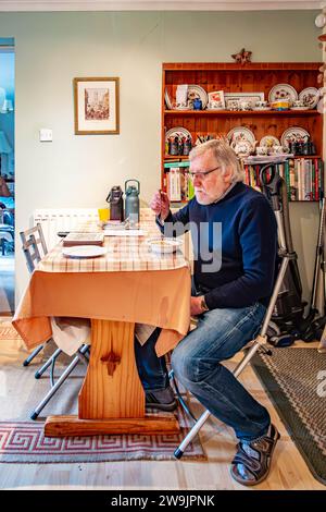 A man sat at a kitchen table eating breakfast Stock Photo