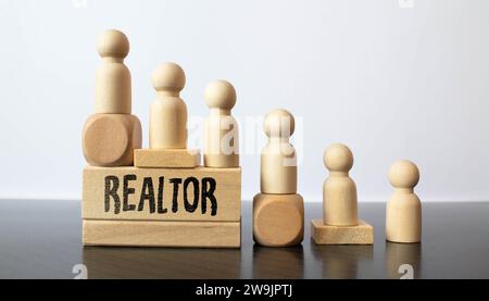 Someone hand and wooden hand together holding colored wood with word REALTOR Stock Photo