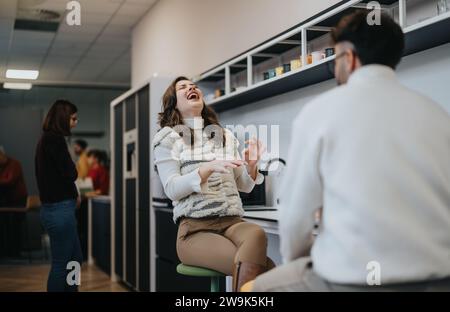 Female employee laughing while having fun conversation with her male coworker during break at work. Stock Photo