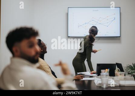 Diverse coworkers collaboratively analyze statistics and strategize business growth in boardroom meeting. Stock Photo