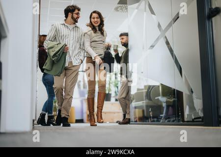 Young employees discussing and smiling as they are leaving the office after working hours. Stock Photo