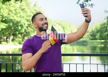 Young man with flag of Germany taking selfie in park Stock Photo
