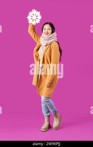 Beautiful young Asian woman in warm scarf with snowflake on purple background Stock Photo