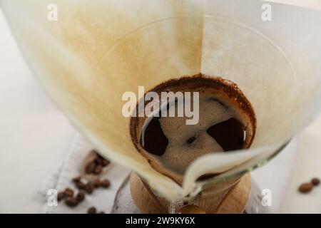 Brewing aromatic drip coffee in chemex coffeemaker with paper filter on table, closeup Stock Photo