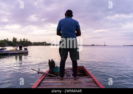 Cabimas, Venezuela. 28th Dec, 2023. A fisherman stands on his boat at sunrise while going fishing. After being exploited for intense oil extraction for decades, Lake Maracaibo has become heavily polluted due to the neglect and lack of maintainance of the old pipes and infrastructure. This has caused a severe decline in fish stock, with the appearance of bacterias and toxic algae on the water surface, damaging the lives of the people living on its shores who rely on fishing for a living. Credit: SOPA Images Limited/Alamy Live News Stock Photo