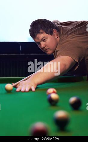 Man playing pool, game and aim with cue and ball, social event at sports bar or restaurant for contest. Competition, focus and serious player Stock Photo