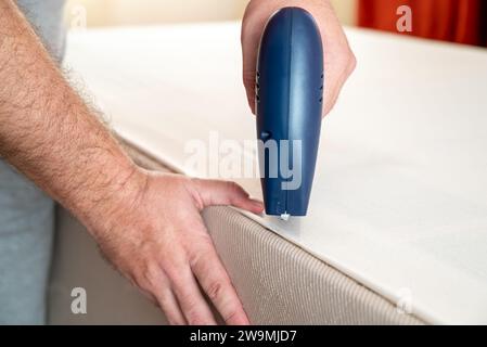 Worker stapling sofa lining with electric staple gun Stock Photo