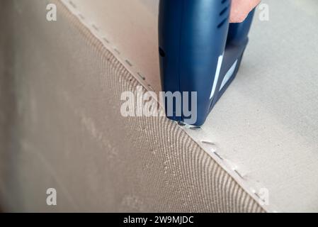Worker stapling sofa lining with electric staple gun Stock Photo