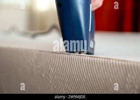 Worker stapling sofa lining with electric staple gun Stock Photo