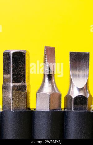 Screwdriver bits in a row on yellow background close up Stock Photo