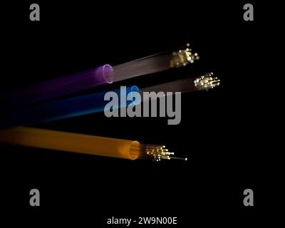 Fibre optic LED lights threaded through three straws against a black background Stock Photo