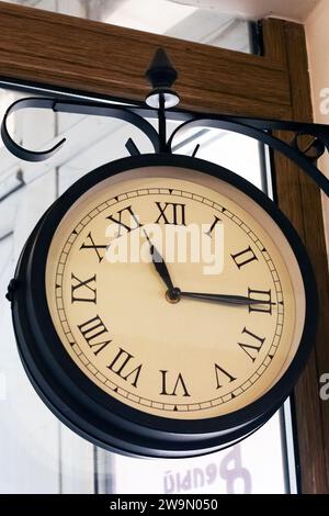 Retro clock with arrows on the wall close up Stock Photo