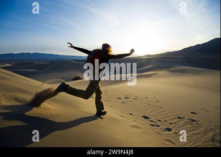 A young woman runs down the sand dunes in Death Valley National Park, CA. Stock Photo