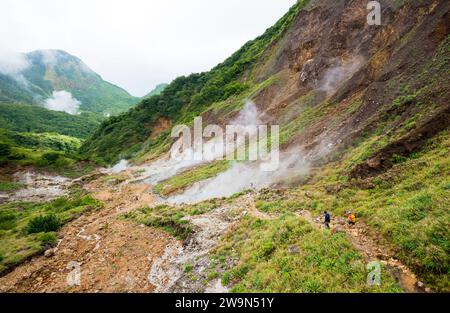 A woman and her guide hike down into the Valley of Desolation on their way to Boiling lake on the Caribbean island of Dominica. Boiling Lake is situated in the Morne Trois Pitons N Stock Photo