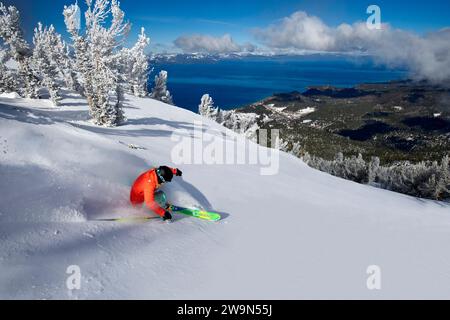 A female skier (Hazel Birnbaum) skis in deep powder on a beautiful day at Heavenly Mountain Resort with Lake Tahoe in the background near South Lake Tahoe, California. Stock Photo