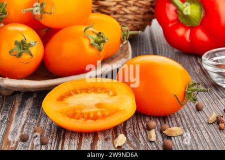 sliced orange plum tomato on wood background Stock Photo