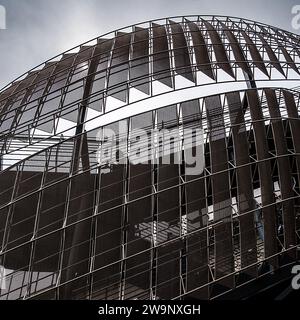 Black & white close-up of modern architectural structure, with curved design, & intricate geometric patterns & silhouette of a person in the middle. Stock Photo