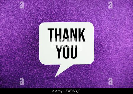Thank You text message in white bubble speech top view on purple background Stock Photo