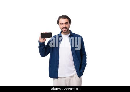 young smart caucasian man with black hair dressed in a blue shirt and t-shirt shows the phone screen Stock Photo