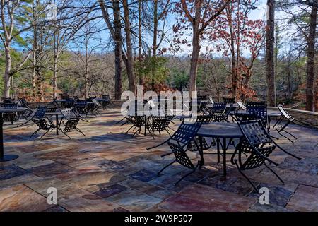 A restaurant outside patio area in a park closed with outdoor metal table and chairs in clusters on a colorful flat stone ground and with hanging ligh Stock Photo