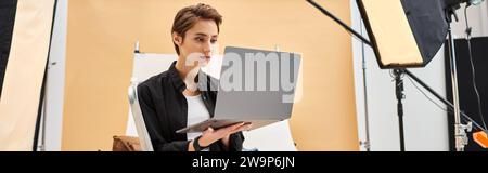 pretty short haired photographer sitting and retouching photos in studio using her laptop, banner Stock Photo