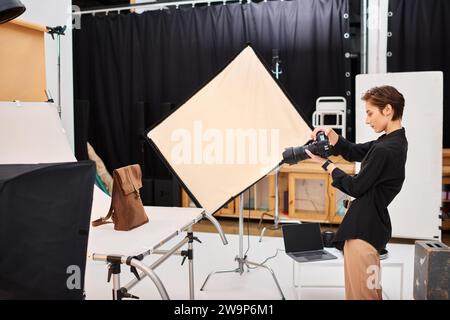 beautiful talented female photographer taking photos of brown leathered backpack in her studio Stock Photo