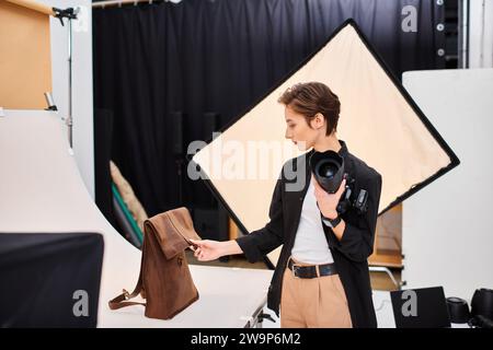 pretty talented female photographer preparing to take photos of brown leathered backpack in studio Stock Photo