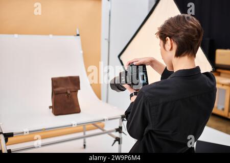 attractive talented female photographer taking photos of brown leathered backpack in her studio Stock Photo